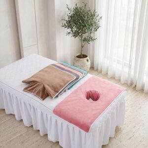 Pink face hole towel on a massage bed with a stack of colour options