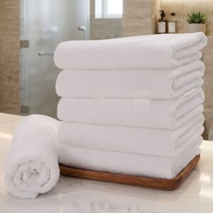Pack of 10 white salon towels stacked, with one towel hanging on a rack